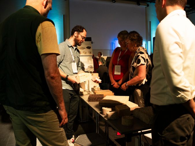 Menschen lassen sich an einem Stand von einem Aussteller Materialien erklären.