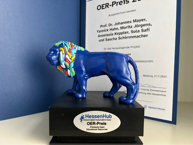 Blauer Löwe mit bunter Mähne auf Sockel (OER-Preis) im Vordergrund, Urkunde im Hintergrund