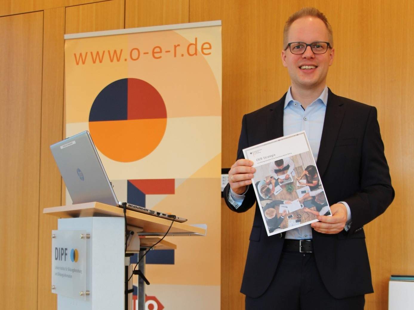 Dr. Jens Brandenburg mit der OER-Strategie als Printversion in Händen