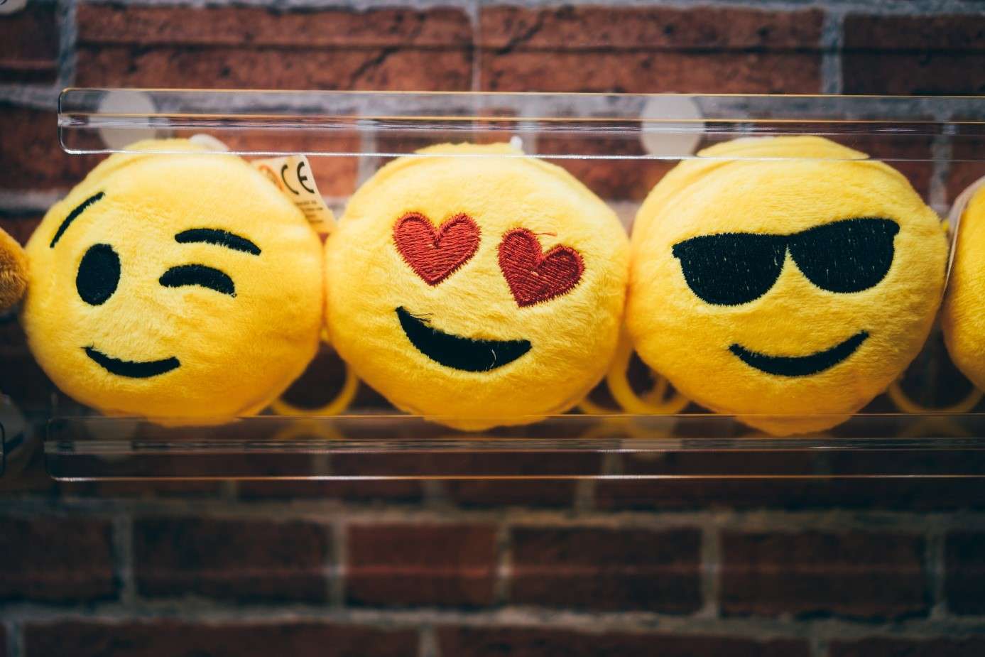 Icons, Emoticons und Emojis: gelbe, flauschige Emoji-Anhänger mit einem zwinkernden Auge,roten Herzen als Augen und einer schwarzen Sonnenbrille