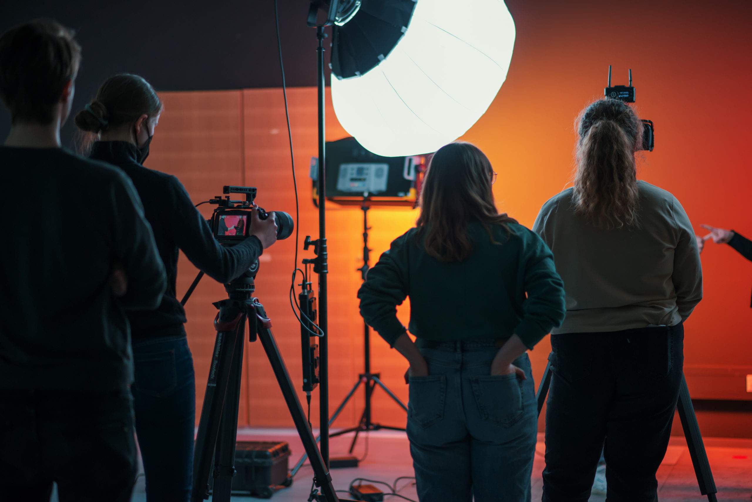 Das Filmteam der OMA unterstützt Studierende beim Erstellen von OER, vier Personen mit dem Rücken zum Betrachter, mit Kamera- und Beleuchtungsausrüstung