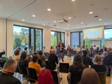 Stuhlkreis mit verschiedenen Reihen, Moderation durch Johannes Appel in der Mitte