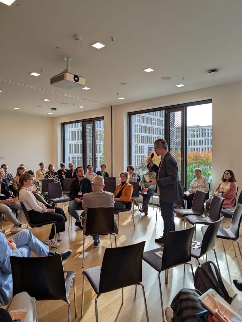 Stuhlkreis mit verschiedenen Reihen, Moderation durch Johannes Appel, 4 diskutierende Personen sitzen im inneren Stuhlkreis