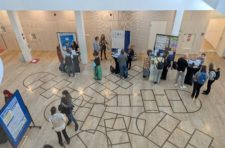 Blick aus dem ersten Stock ins Foyer des DIPFs. Menschen stehen um Stehtische und Pinnwände